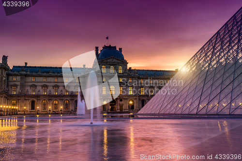 Image of View of famous Louvre Museum with Louvre Pyramid at evening. 