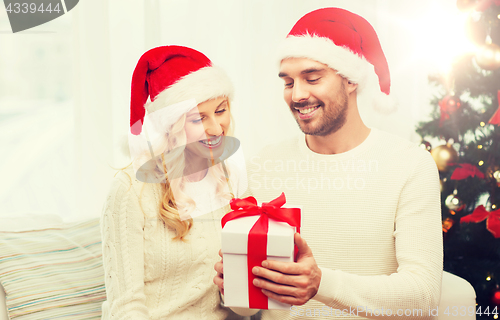 Image of happy couple at home with christmas gift box