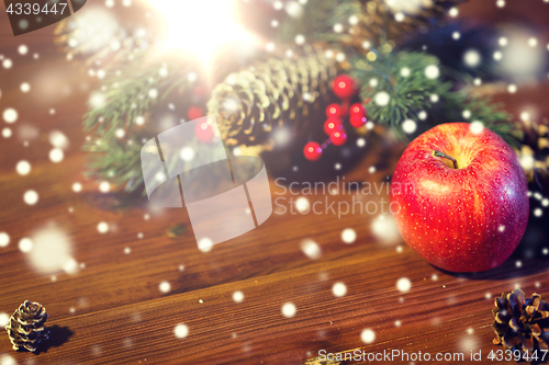 Image of close up of apple with fir decoration on wood