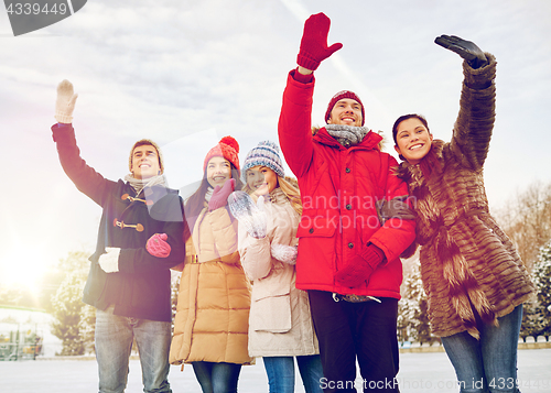 Image of happy friends waving hands outdoors