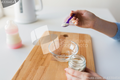 Image of hands with spoon and jar making baby cereal