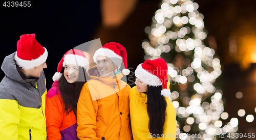 Image of friends in santa hats and ski suits at christmas