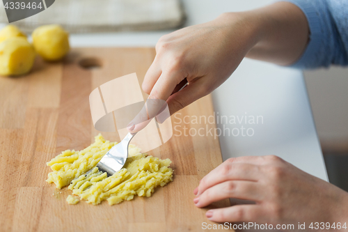 Image of hand with fork making mashed potato on board