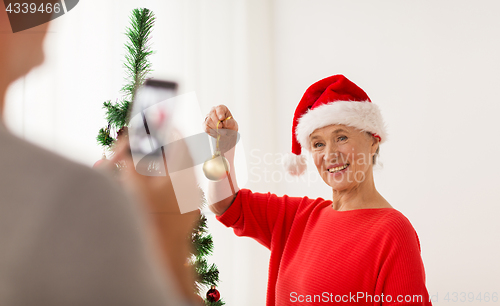 Image of happy senior woman decorating christmas tree