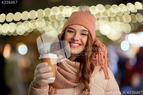 Image of happy woman with coffee over christmas lights