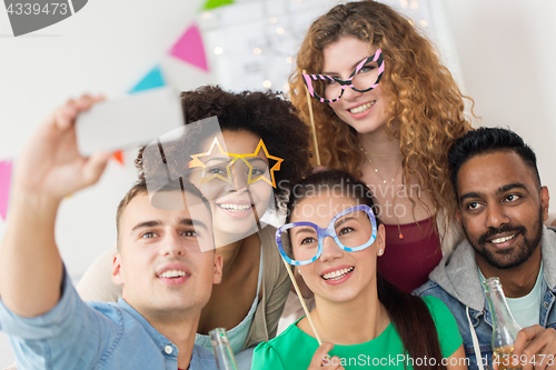 Image of happy friends taking selfie at party