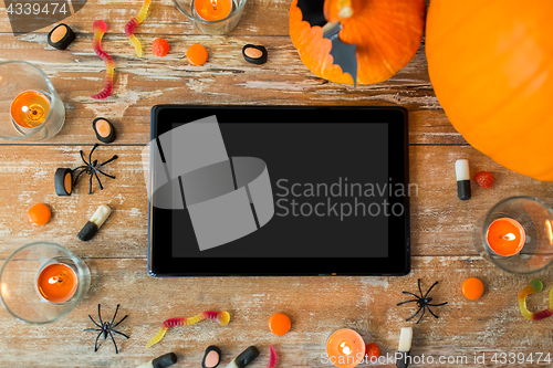 Image of halloween pumpkins, candies, candles and tablet pc