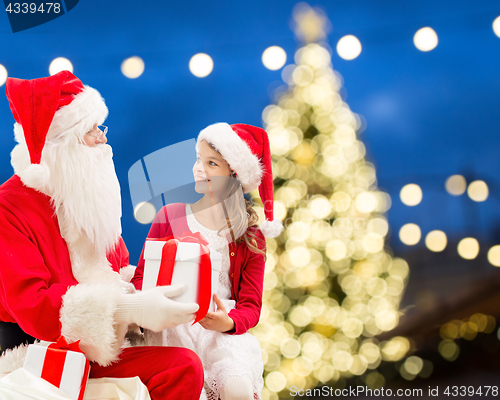 Image of santa claus and happy girl with christmas gift