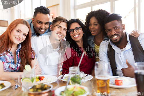 Image of happy friends eating at restaurant