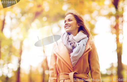 Image of beautiful happy young woman walking in autumn park