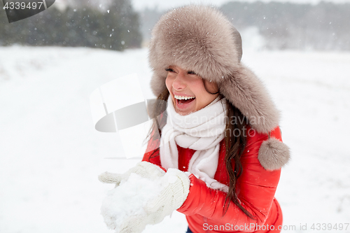 Image of happy woman with snow in winter fur hat outdoors