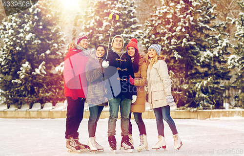 Image of happy friends with smartphone on ice skating rink