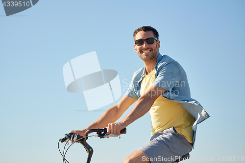 Image of happy smiling man riding bicycle outdoors