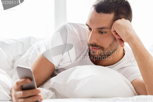 Image of close up of man with smartphone in bed in morning