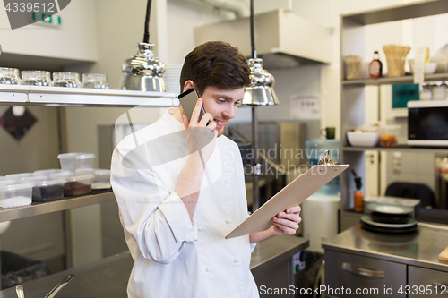 Image of chef cook calling on smartphone at restaurant kitchen