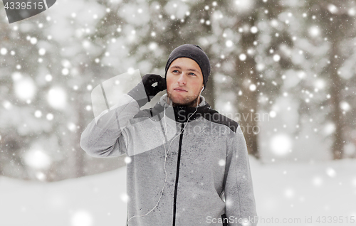 Image of sports man with earphones in winter forest