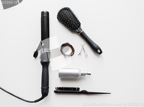 Image of iron, brushes, styling spay, hair ties and pins