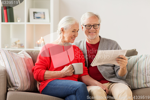 Image of happy senior couple reading newspaper at christmas