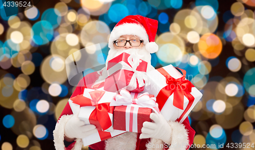 Image of santa claus with christmas gifts over lights