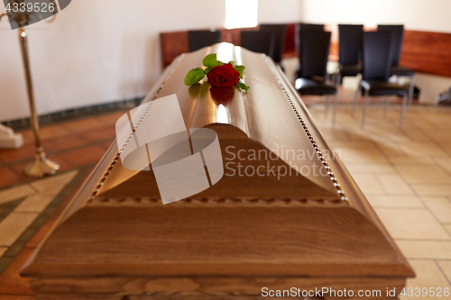 Image of red rose flower on wooden coffin in church