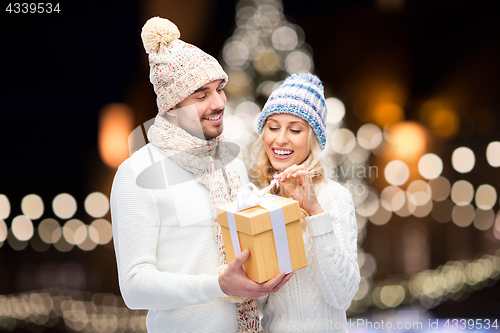 Image of happy couple with christmas gift over night lights