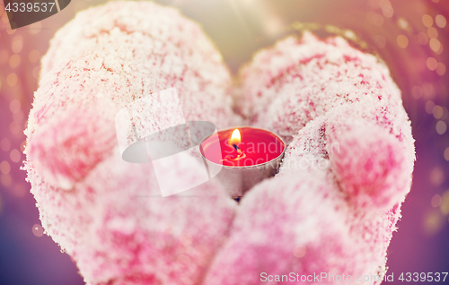 Image of close up of hands in winter mittens holding candle