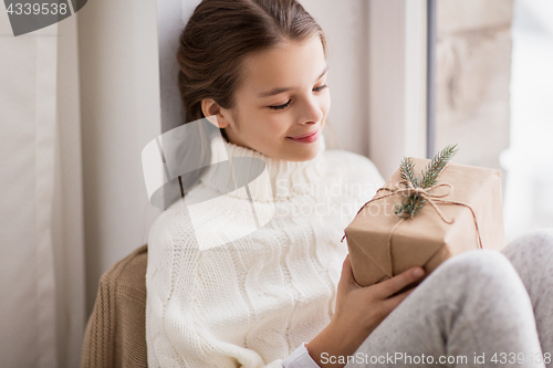 Image of girl with christmas gift sitting at home