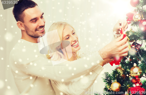 Image of happy couple decorating christmas tree at home