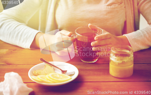 Image of close up of woman adding lemon to tea cup