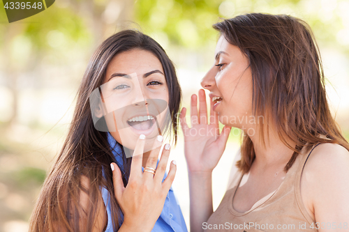 Image of Two Beautiful Ethnic Twin Sisters Whispering Secrets Outdoors.
