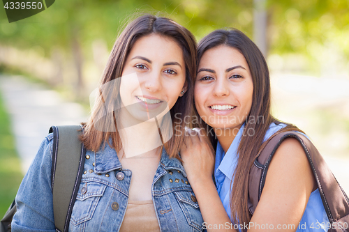 Image of Two Beautiful Young Ethnic Twin Sisters With Backpacks Walking O