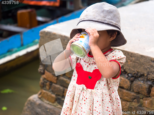 Image of Small girl drinking sweetened, condensed milk