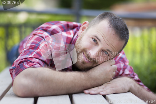 Image of bearded handsome man lying on a bench