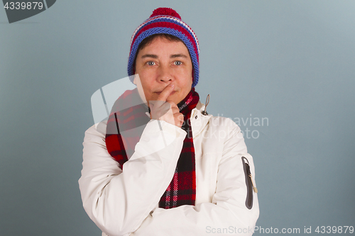 Image of Woman in winter clothes puts finger on her mouth