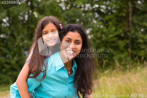 Image of Smiling mother giving piggyback to daughter