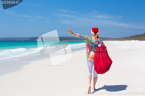 Image of Christmas in Australia - festive woman walking along idyllic bea