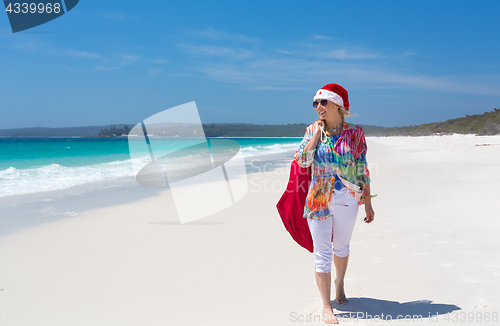 Image of Christmas down on the beach summer sun female walking with santa