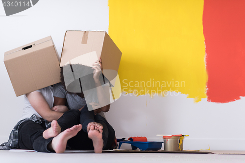 Image of young multiethnic couple playing with cardboard boxes