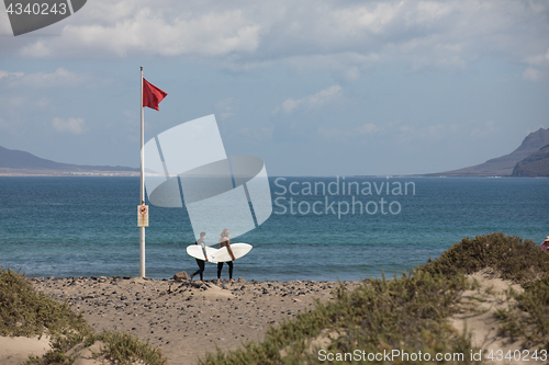 Image of The red flag weighs in the wind at Surfers Beach Famara on Lanza