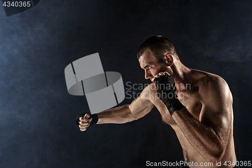 Image of The young man kickboxing on black