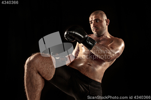 Image of The young man kickboxing on black