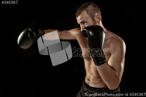 Image of The young man kickboxing on black