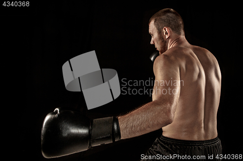 Image of The young man kickboxing on black