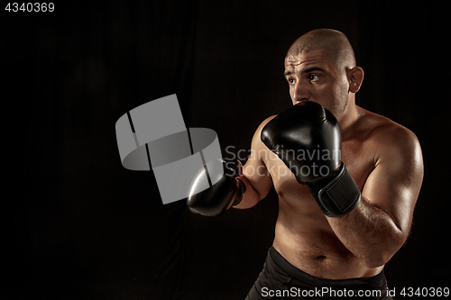 Image of The young man kickboxing on black