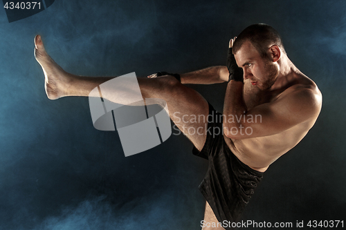 Image of The young man kickboxing on black