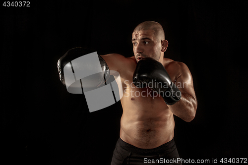 Image of The young man kickboxing on black