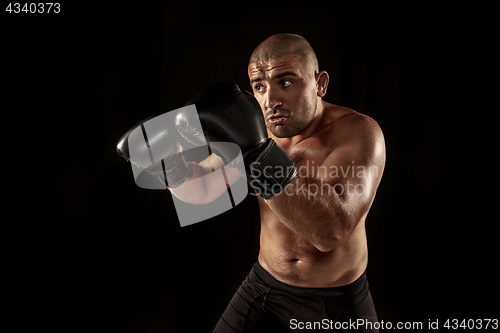 Image of The young man kickboxing on black