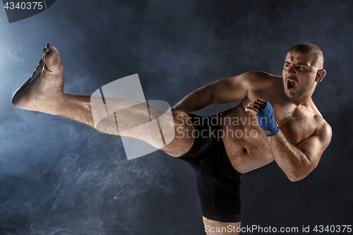 Image of The young man kickboxing on black