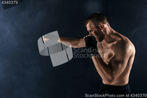 Image of The young man kickboxing on black