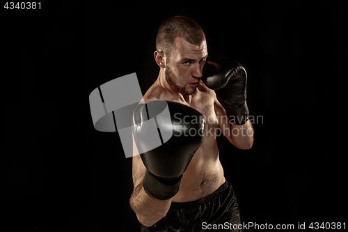 Image of The young man kickboxing on black